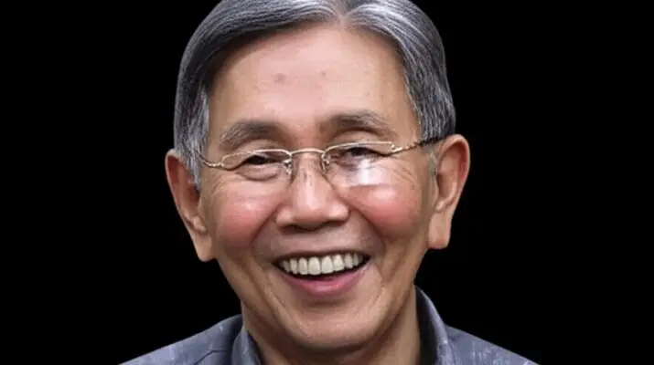 Foto close-up Kwik Kian Gie tersenyum ramah dengan latar belakang hitam.